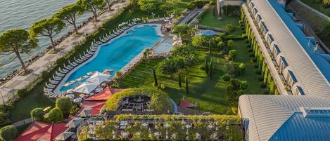 Una piscina techada, una piscina al aire libre, sombrillas