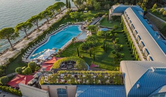 Μια αεροφωτογραφία ενός θέρετρου με μια μεγάλη πισίνα, ξαπλώστρες και έναν καλά περιποιημένο κήπο.