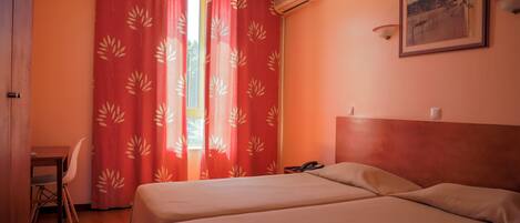 A room with two beds, a desk, and a chair.