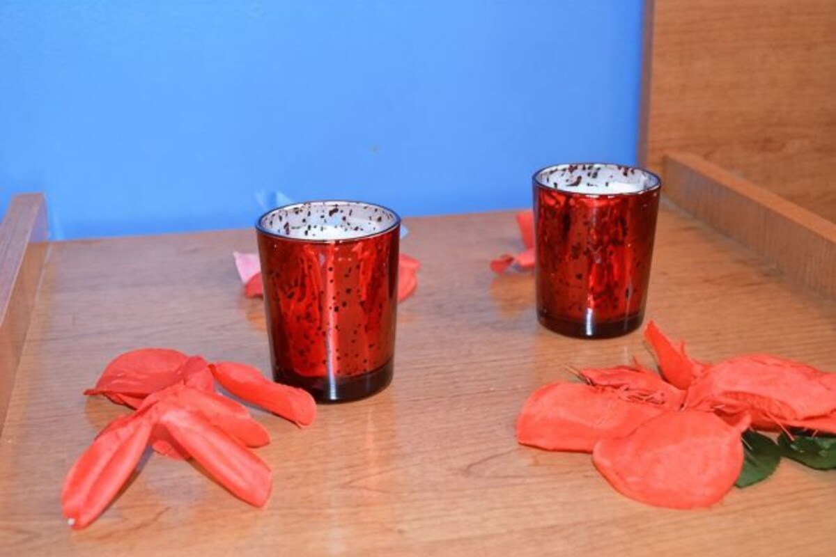 Dos tazas rojas sobre una bandeja de madera con hojas rojas.