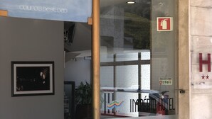 The interior of the Império Hotel with a reception desk, a framed picture on the wall, and a glass door leading outside. - Império Hotel (Peso da Régua)