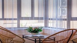A room with a glass table, two wicker chairs, a potted plant, and sheer curtains. - Império Hotel (Peso da Régua)
