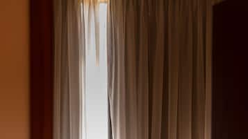 A room with a bed, a radiator, and sheer curtains allowing natural light.