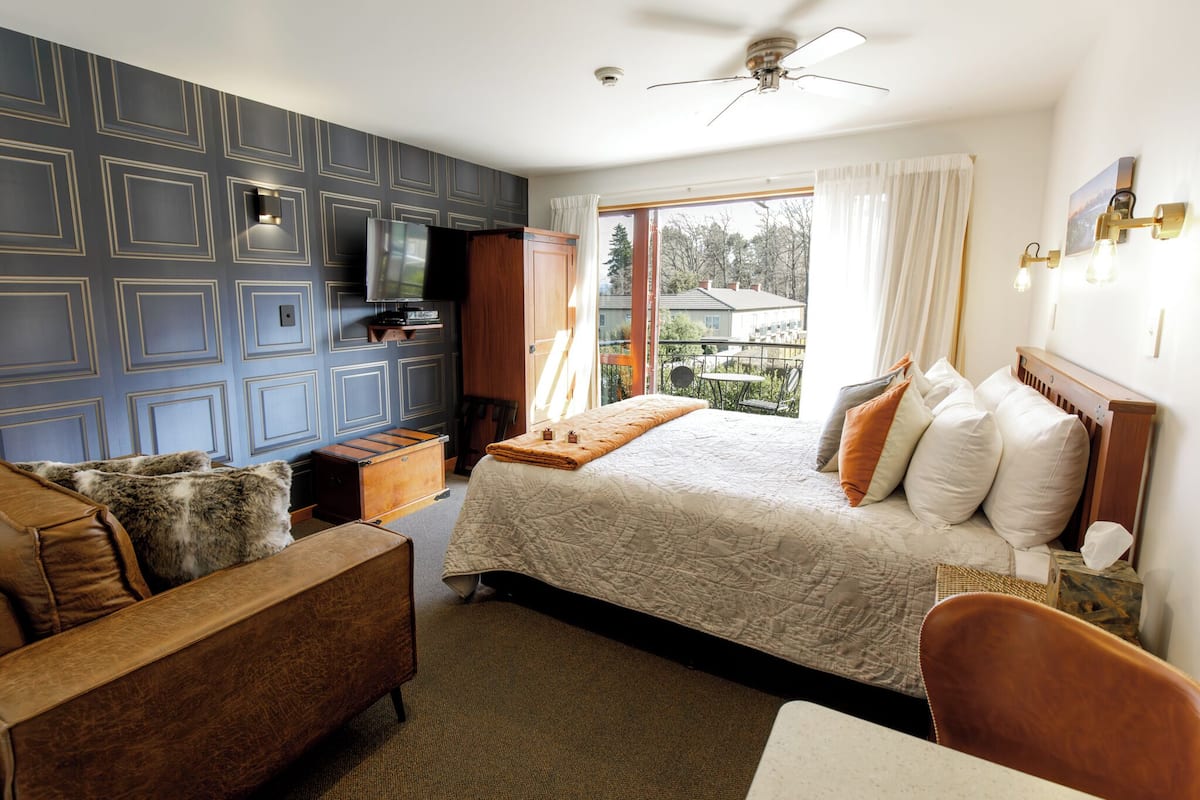 Un dormitorio con una cama grande, un sofá, un televisor y vistas al exterior.