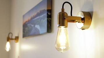 A wall-mounted light fixture with a clear glass bulb and a gold-colored base.