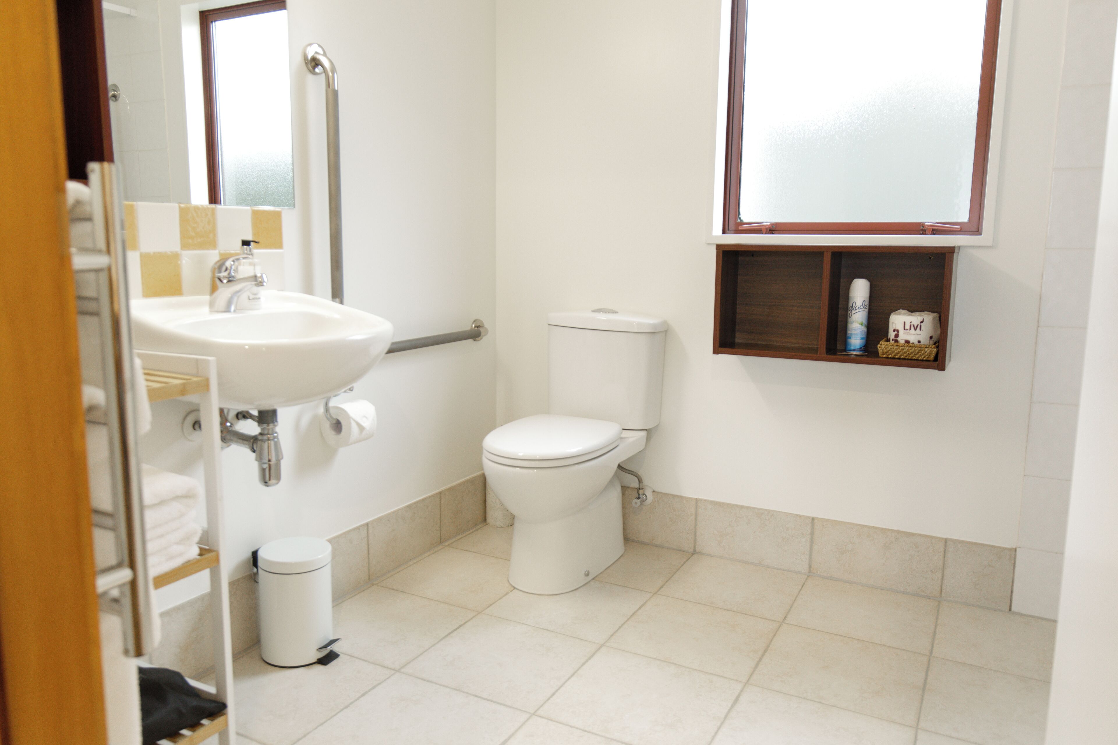 A bathroom with a sink, toilet, and a small shelf with toiletries.