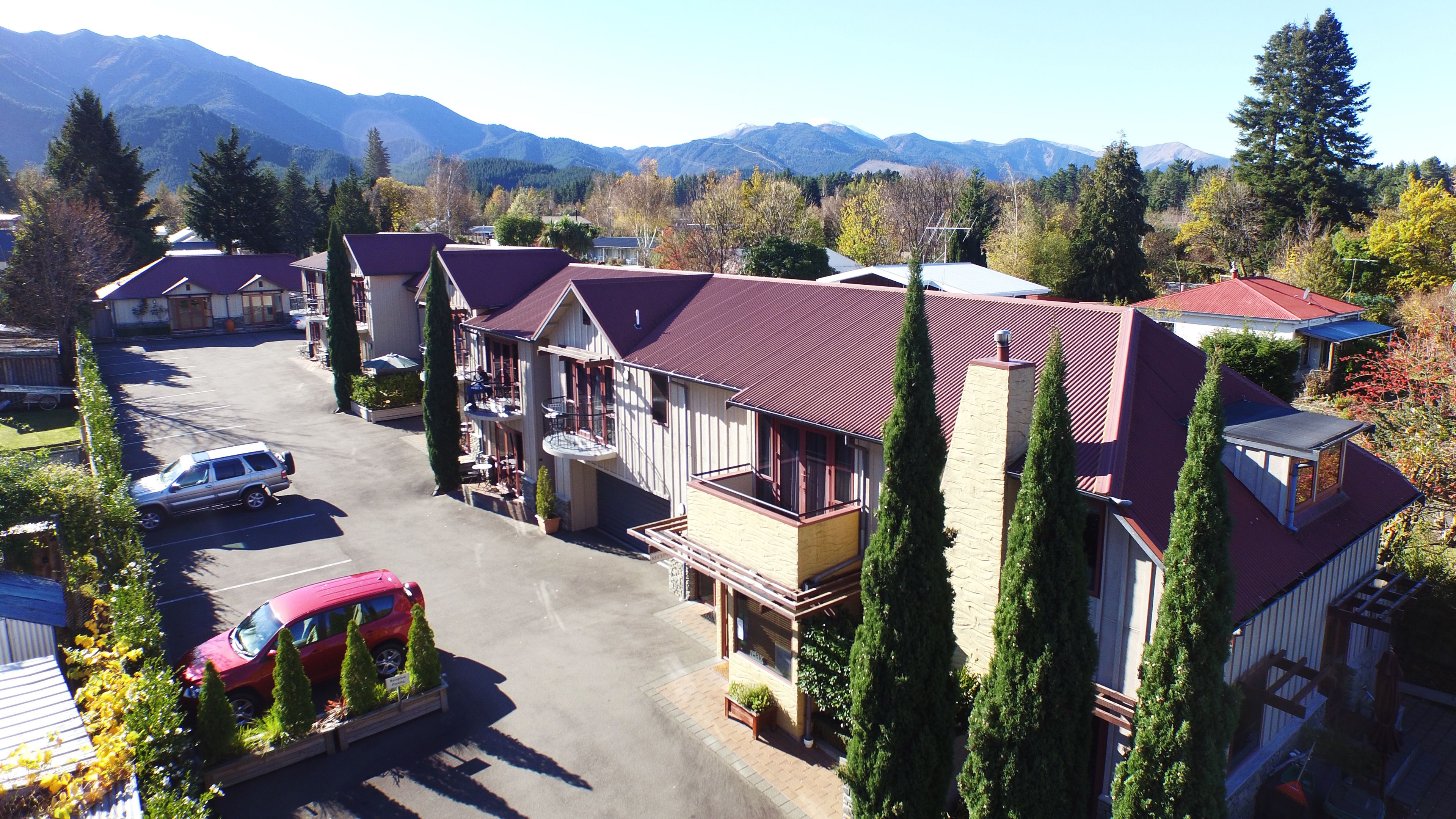 A residential area with houses featuring red roofs, a parking lot, and a mountainous backdrop.