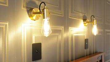 Wall-mounted light fixtures with exposed bulbs, a switch, and a wooden railing.