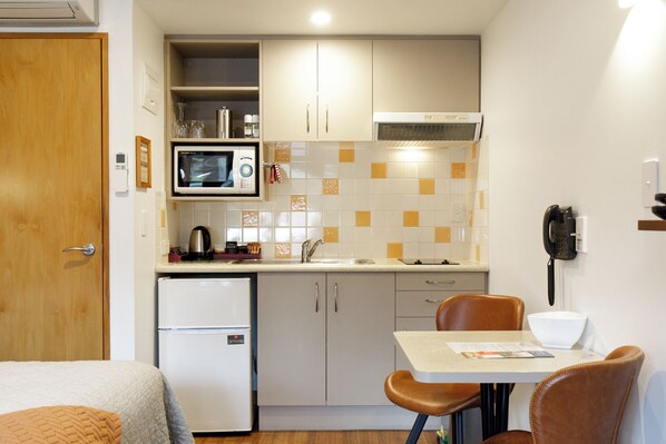 Una cocina compacta equipada con microondas y refrigerador, y un comedor con mesa y sillas.