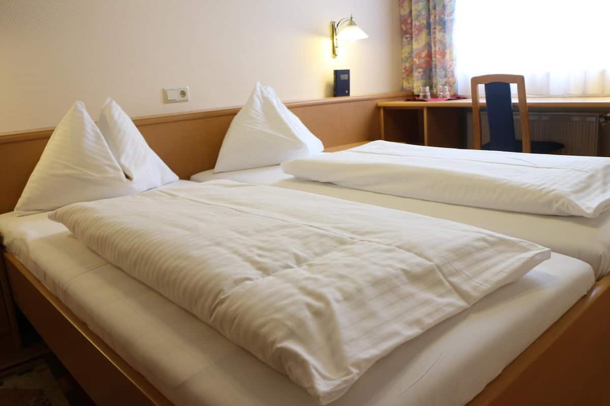 A hotel room with two beds, a desk, and a chair.