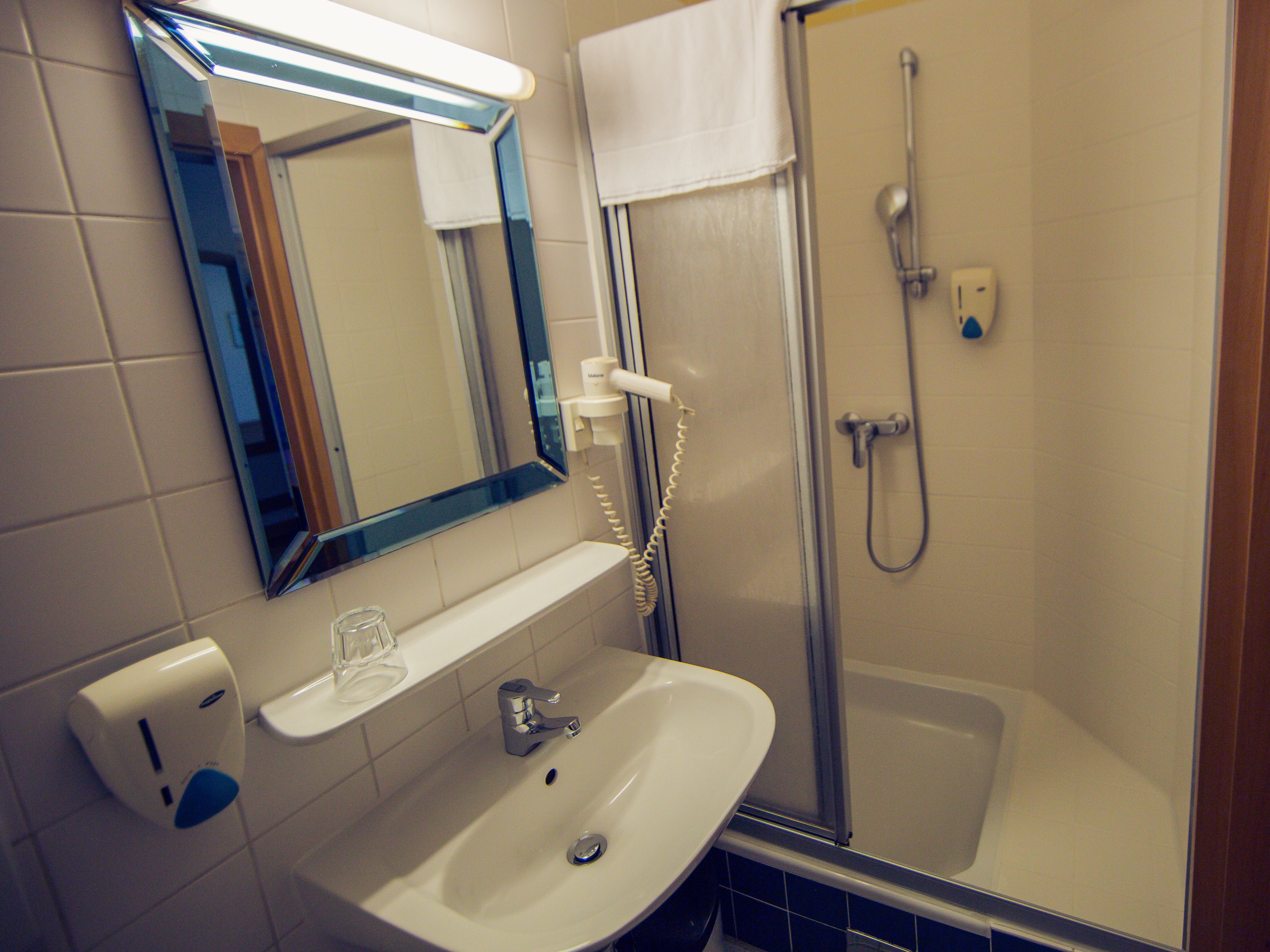 Un baño con lavamanos, espejo y ducha.