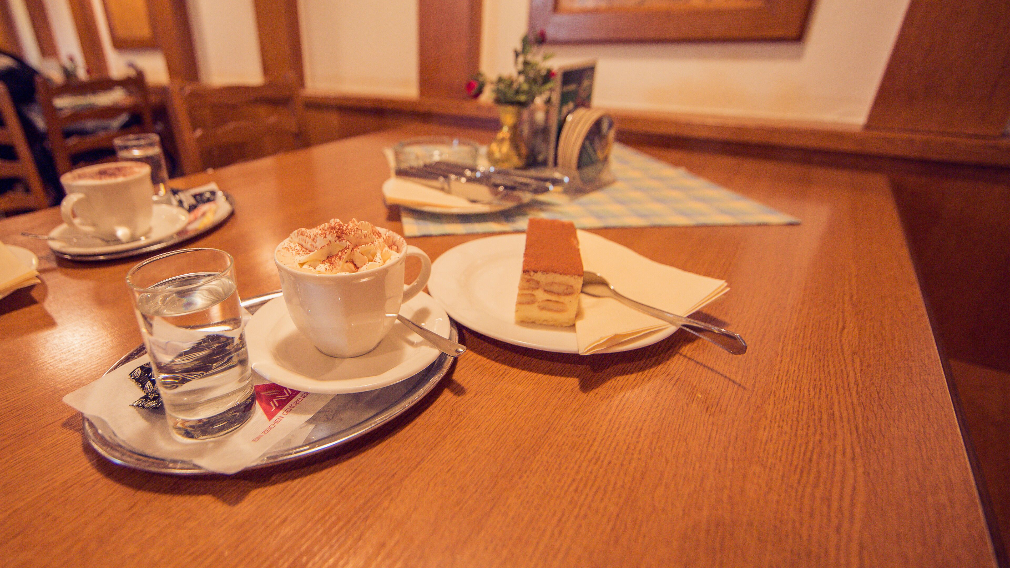 A table set with a dessert, a cup of coffee, and a glass of water.