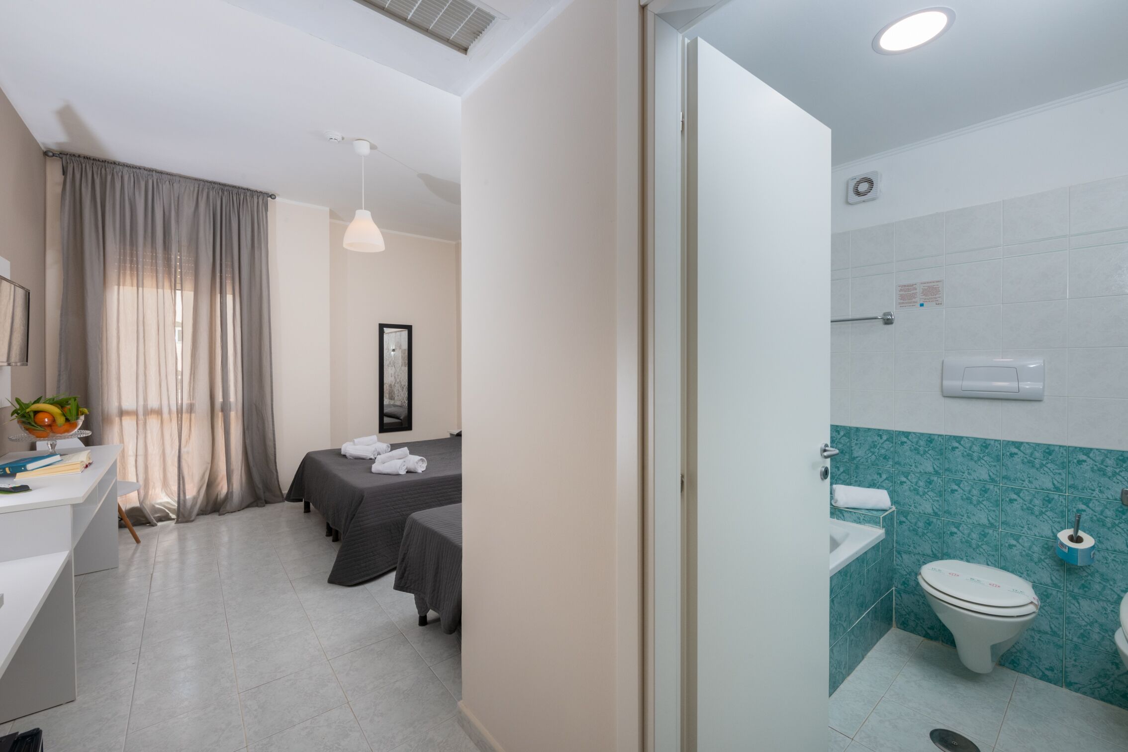Una habitación de hotel con cama, mesita de noche y baño con inodoro y lavamanos.