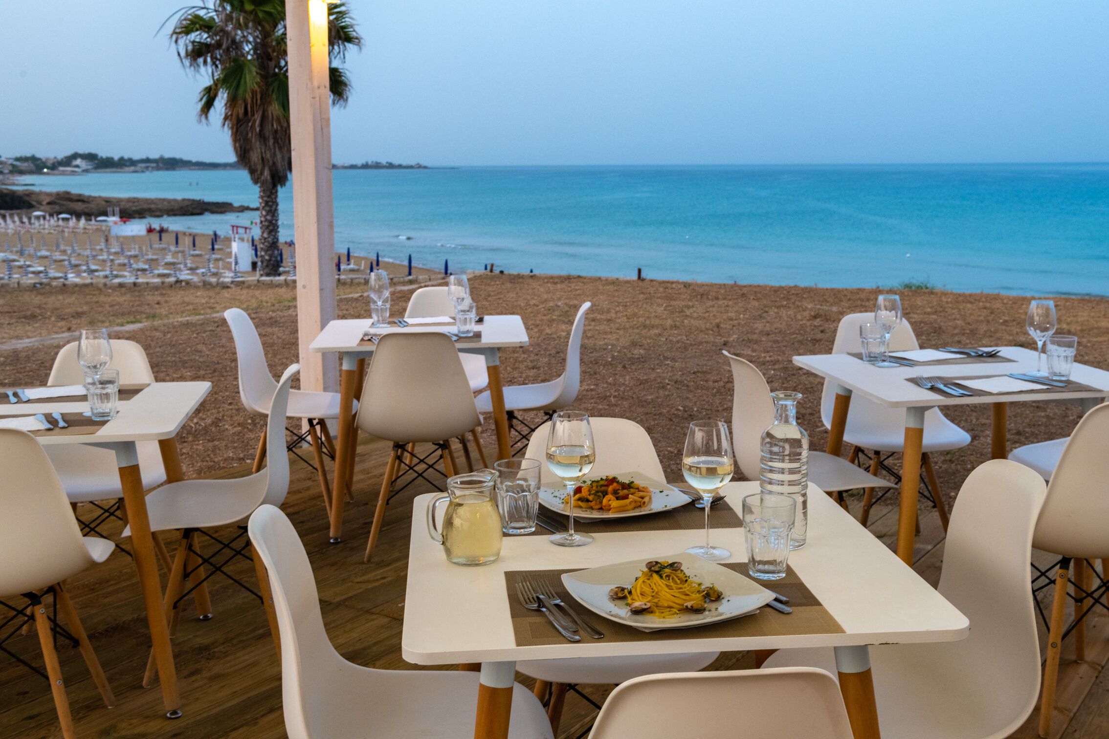 Ein Restaurant am Meer mit Tischen und Stühlen für Speisen, mit Blick auf den Ozean.