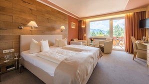 A hotel room with a large bed, two bedside tables, a desk, a chair, and a TV.