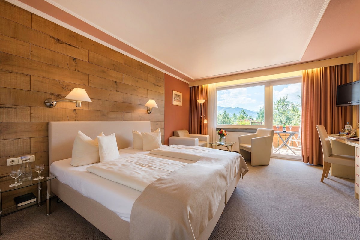 Ein Hotelzimmer mit einem großen Bett, zwei Nachttischen, einem Schreibtisch, einem Stuhl und einem Fernseher.