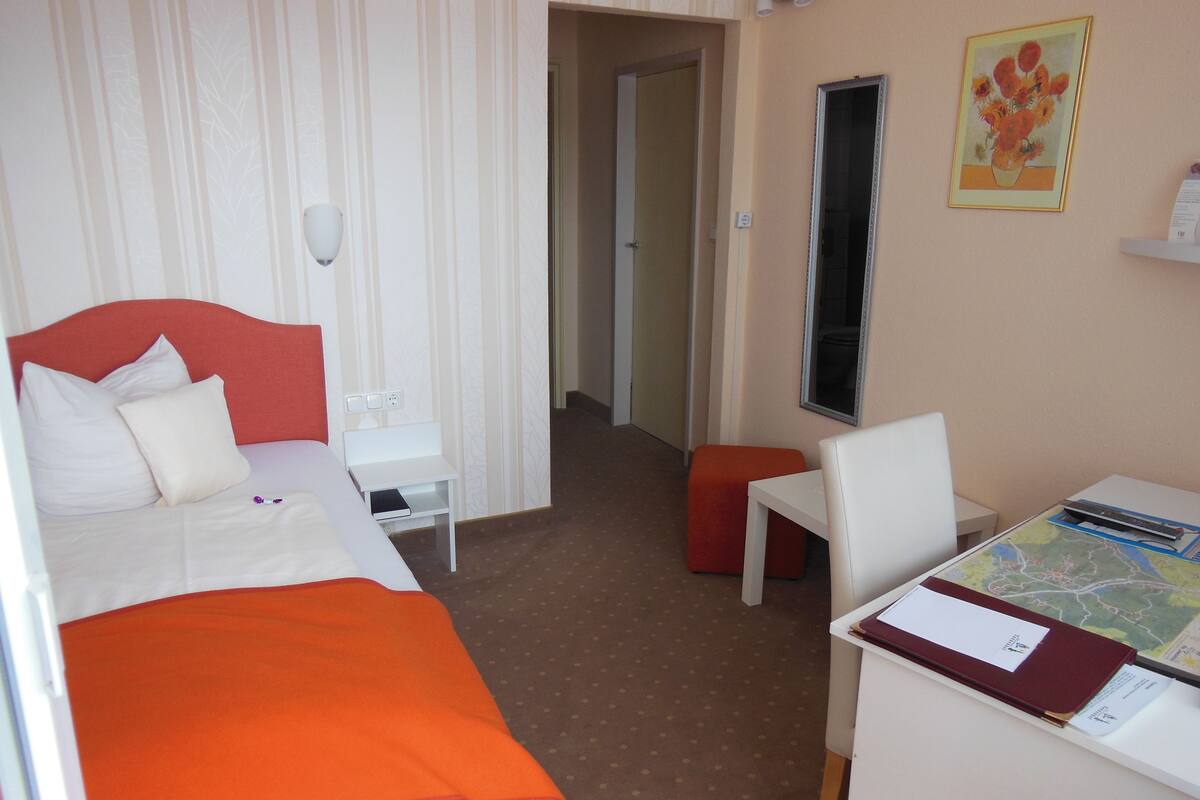 Ein Hotelzimmer mit Bett, Schreibtisch, Stuhl, kleinem Tisch und einer Karte auf dem Schreibtisch.