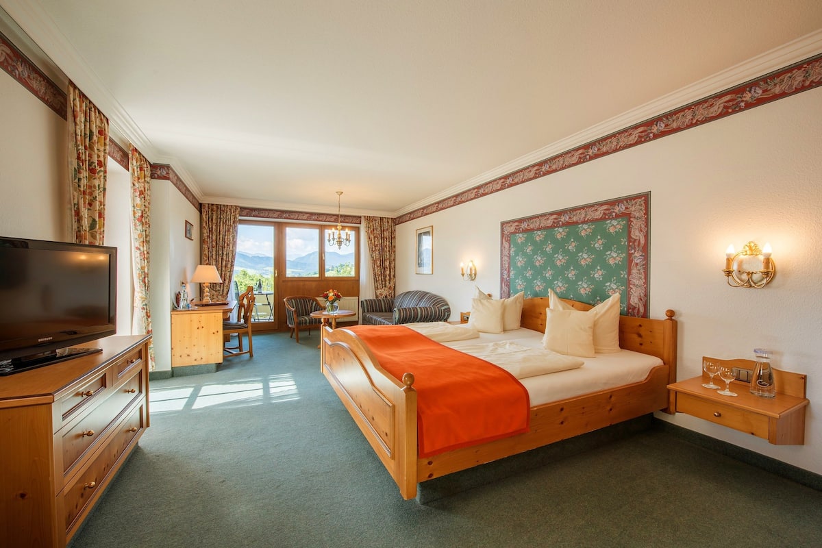 Ein Hotelzimmer mit Bett, Fernseher, Schreibtisch und Stuhl.
