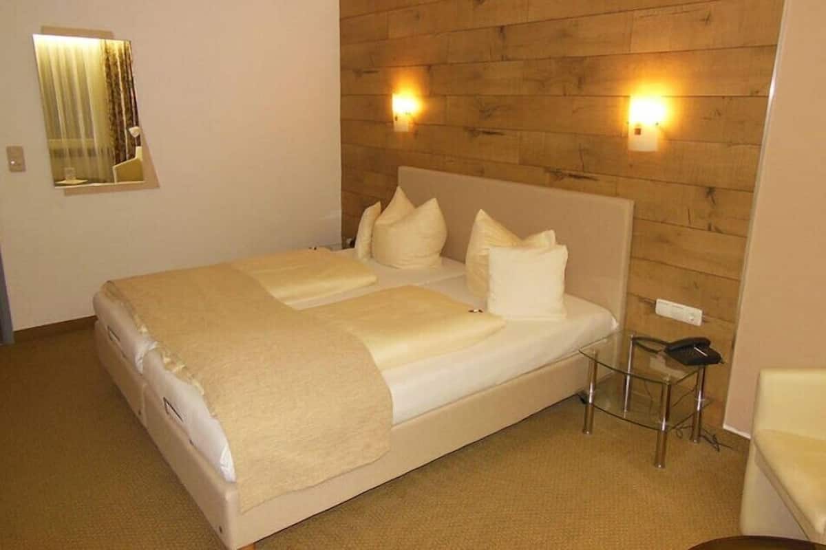 Ein Hotelzimmer mit einem großen Bett, zwei Nachttischlampen, einem Spiegel und einem kleinen Tisch.