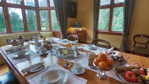 A dining table set with plates, cutlery, and a fruit bowl.