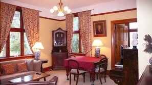Uma sala de estar aconchegante com sofá, mesa de jantar com cadeiras, armário de madeira e lustre.