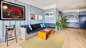 Ein modernes Wohnzimmer mit einem dunkelblauen Sofa, einem Holztisch und einer an der Wand befestigten Bücherablage.