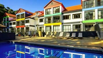 Un hôtel à plusieurs étages doté d’une piscine et de chaises longues.