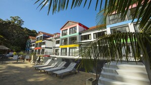 Ein mehrstöckiges Hotel mit farbenfrohen Fassaden und einem Poolbereich mit Liegestühlen.