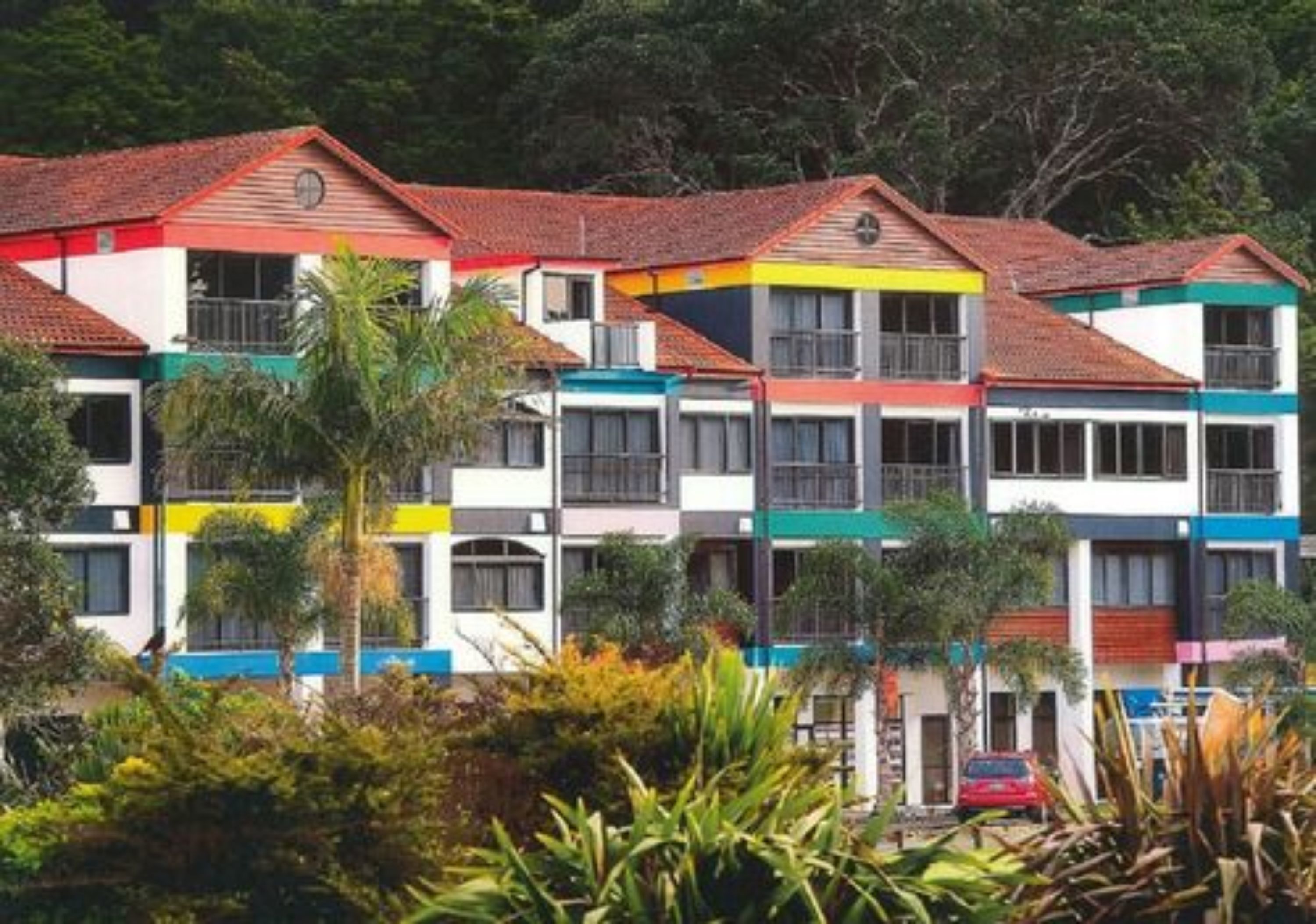 A row of colorful, multi-story buildings with a consistent architectural style, featuring balconies and a uniform roof design.