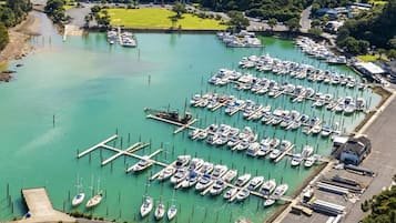 Een jachthaven met veel boten afgemeerd, een parkeerplaats en een gebouw op de achtergrond.