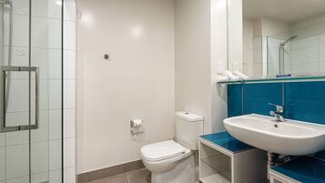 A bathroom with a glass shower enclosure, a white toilet, and a sink with a blue countertop.