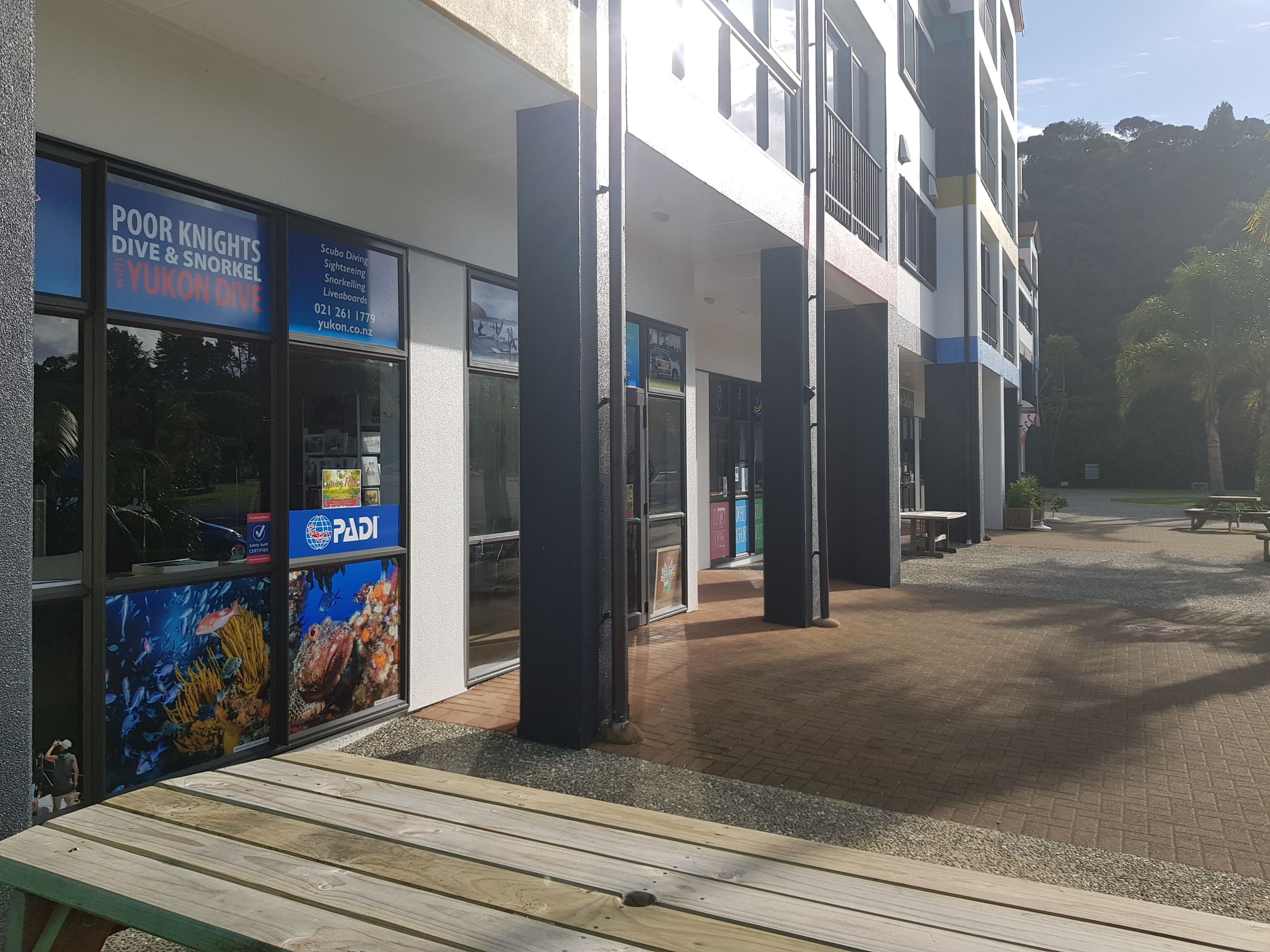 A building with a sign for 'Poor Knights Dive & Snorkel' and a PADI logo.