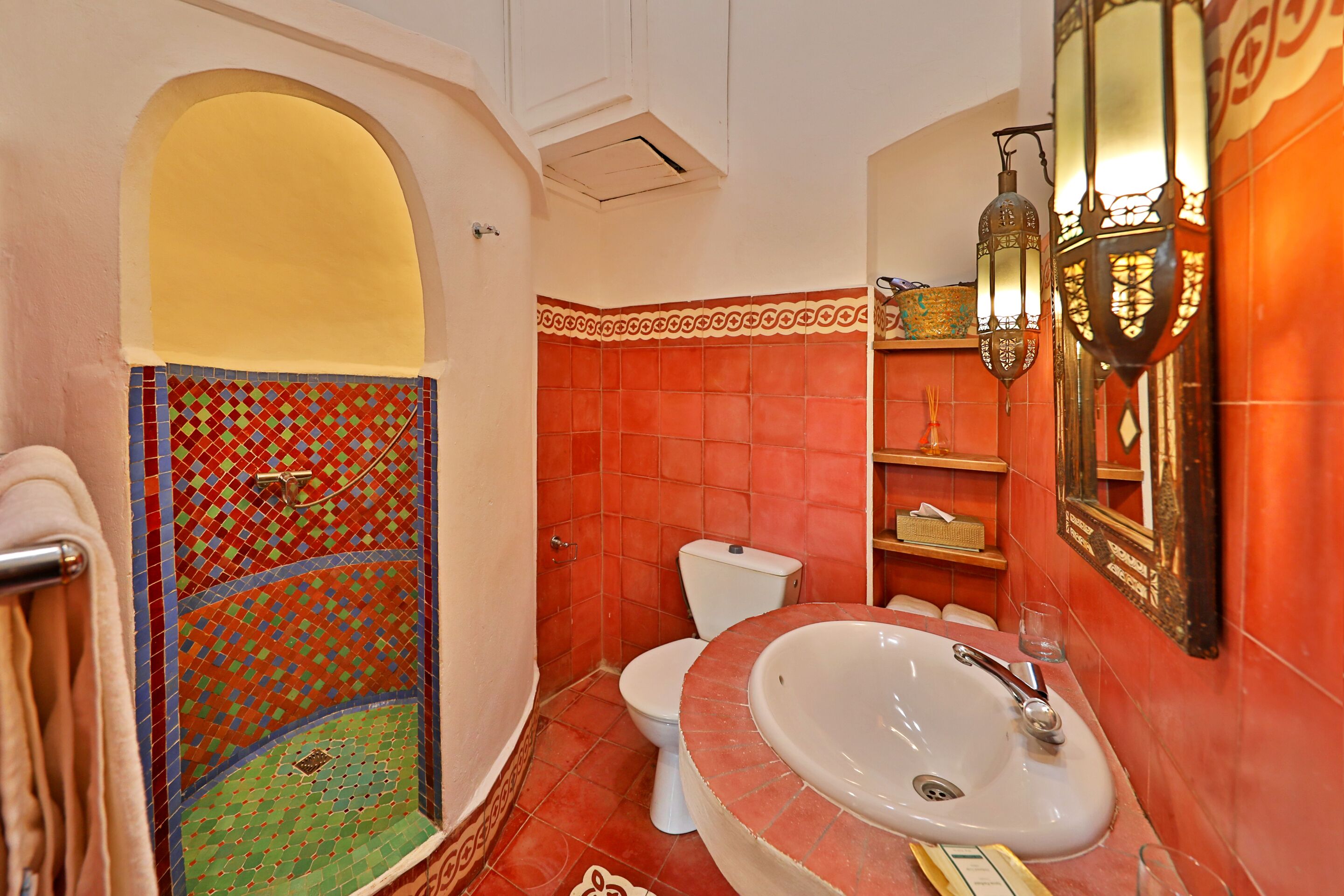 A bathroom with a tiled shower, a toilet, a sink, and a mirror.
