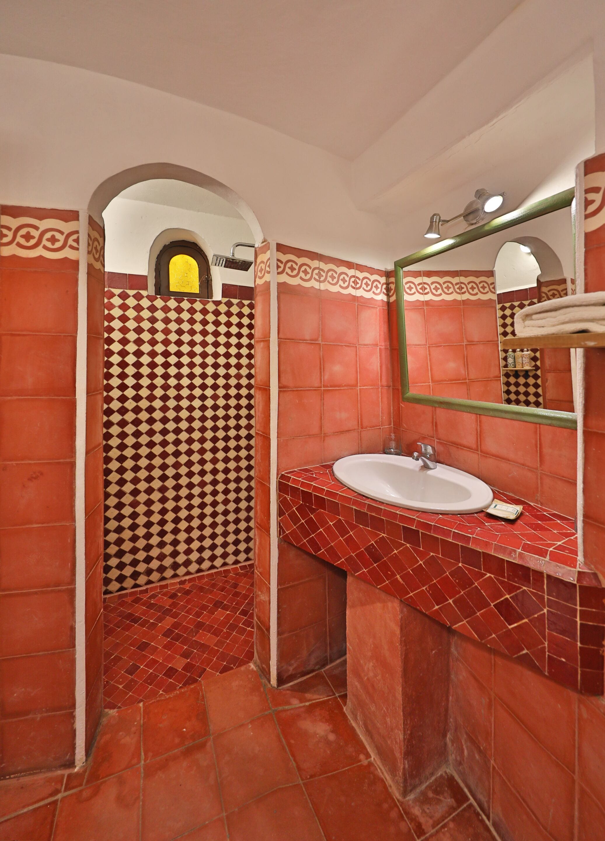 Un baño con piso a cuadros, un lavamanos con espejo y una zona de ducha.