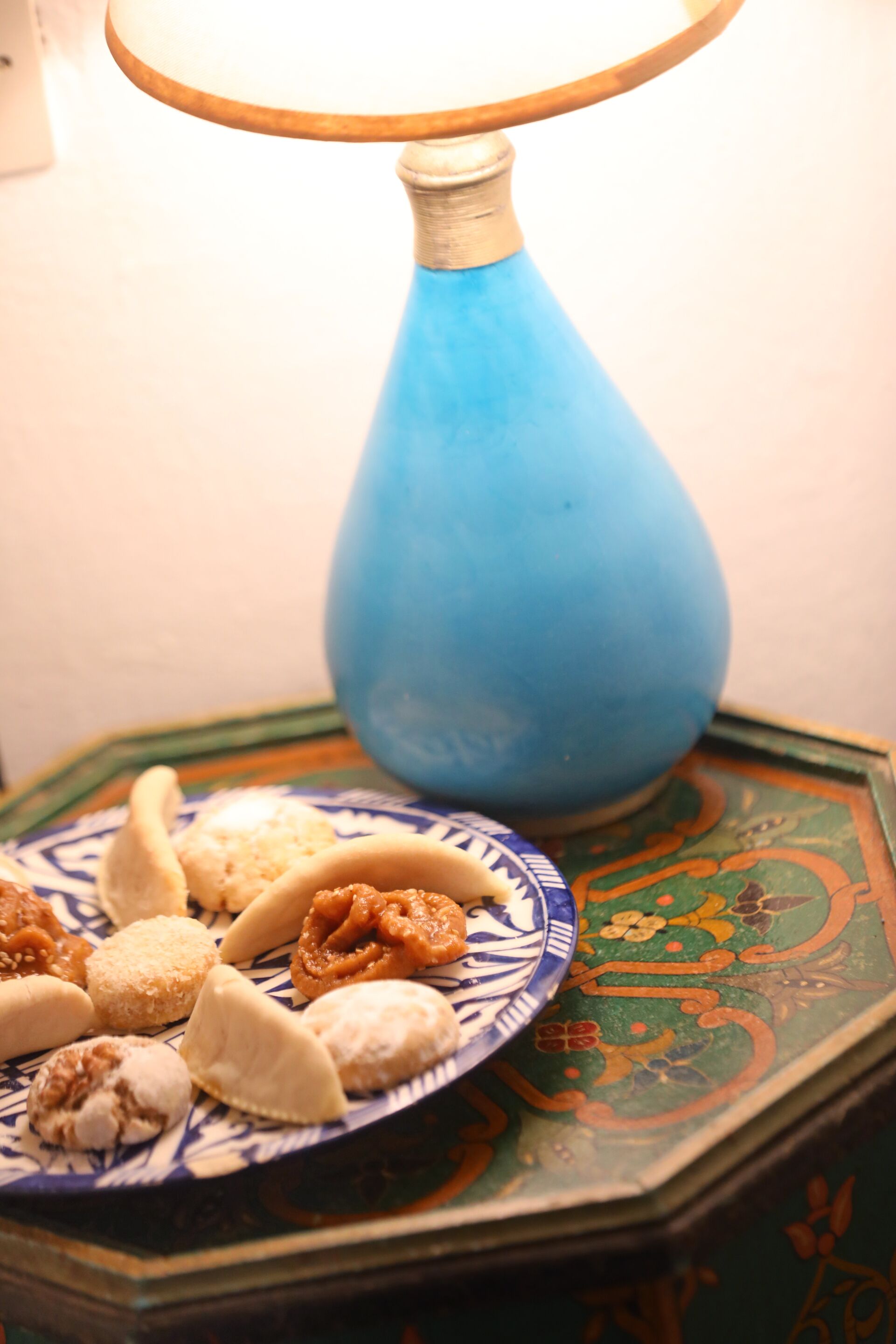 A blue vase on a decorative stand with a plate of assorted pastries.