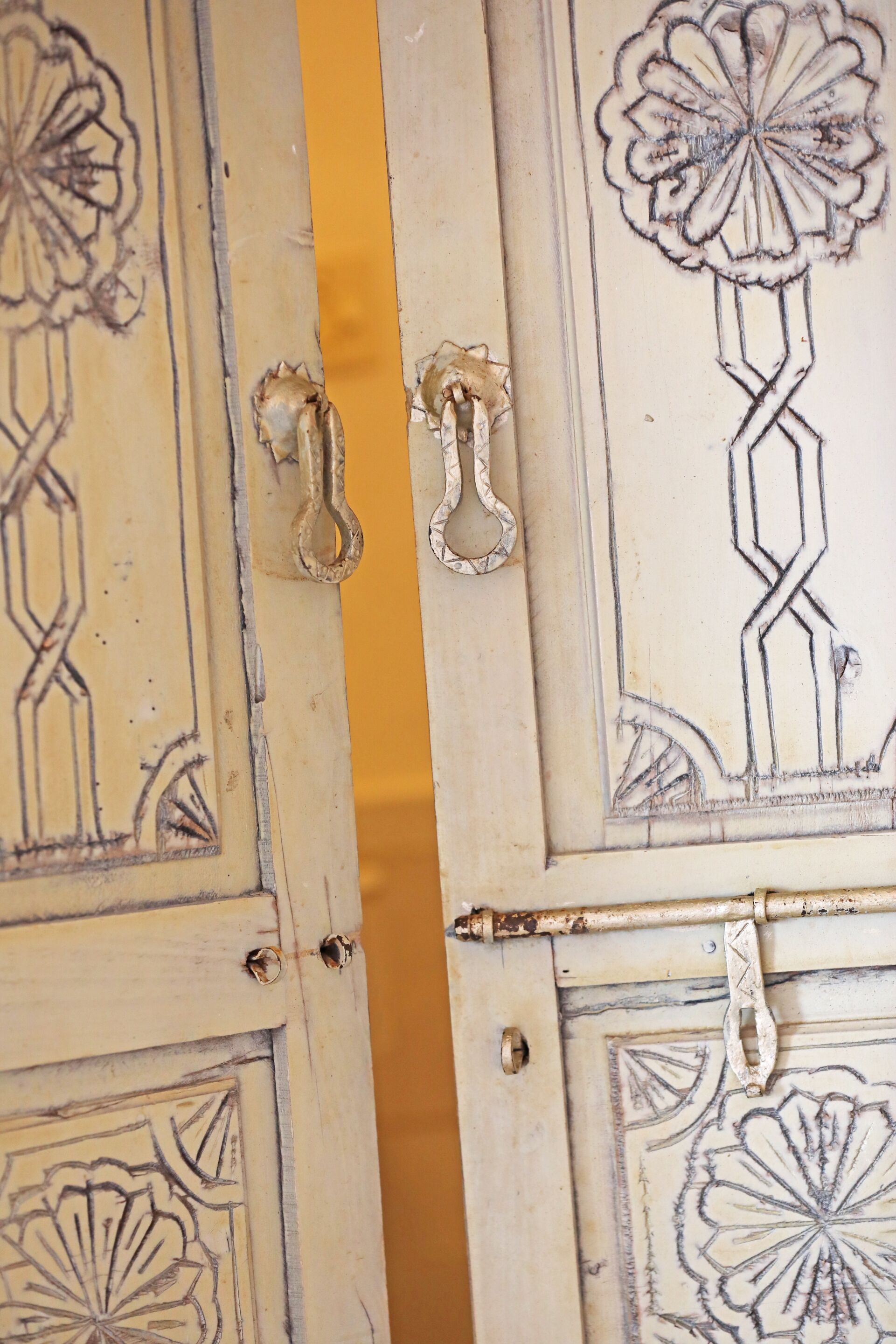 A door with intricate floral and geometric patterns, a brass handle, and a yellow accent.