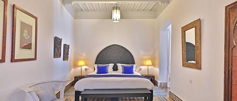 A bedroom with a large bed, two bedside lamps, a chair, and a patterned rug.