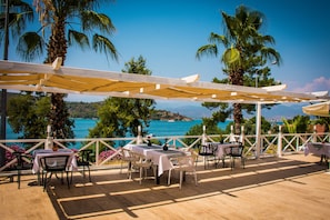 An outdoor patio with tables and chairs, overlooking a scenic coastal view.