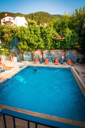 A swimming pool with blue water, surrounded by orange lounge chairs and a blue staircase. - Levent Hotel (Fethiye)