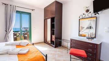 Une chambre d’hôtel comprenant un lit, une armoire, un bureau, une chaise, un banc, un miroir et un téléviseur.