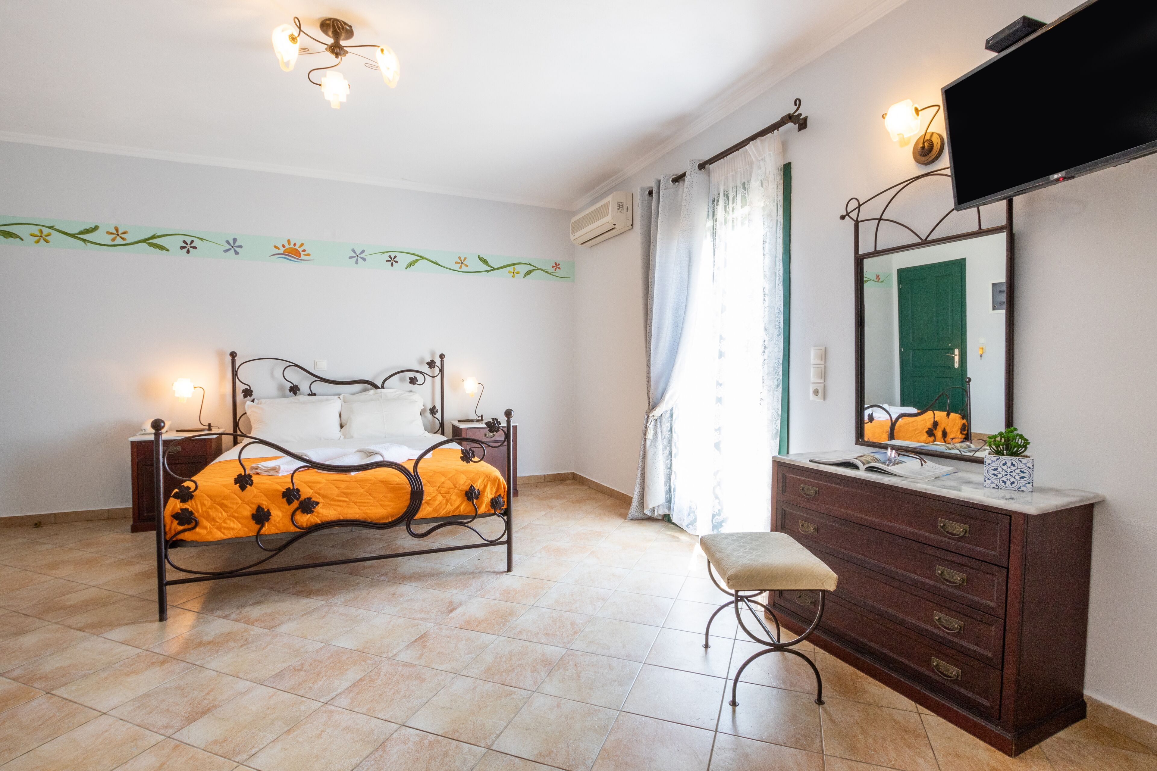 A bedroom with a bed, a dresser, a television, and a window with curtains.