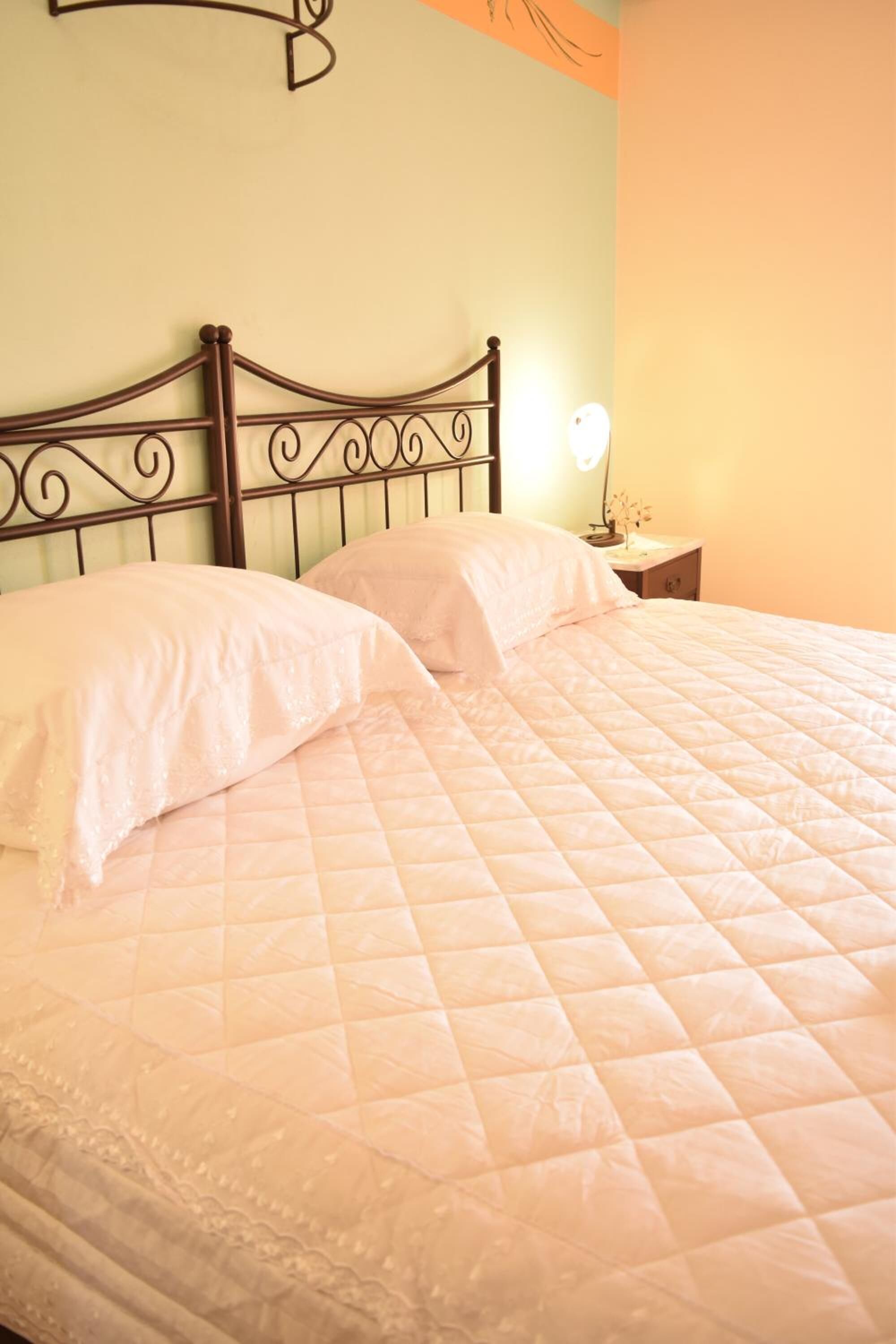 A bed with a quilted mattress and a headboard with a decorative design.