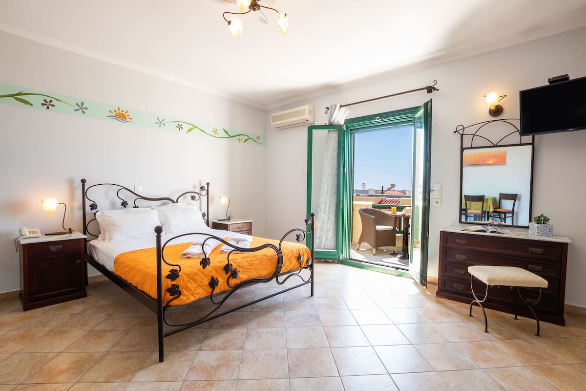A bedroom with a bed, bedside tables, a dresser, a chair, and a TV.