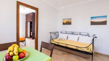 Een kamer met een bed, een eettafel met fruit en een stoel.