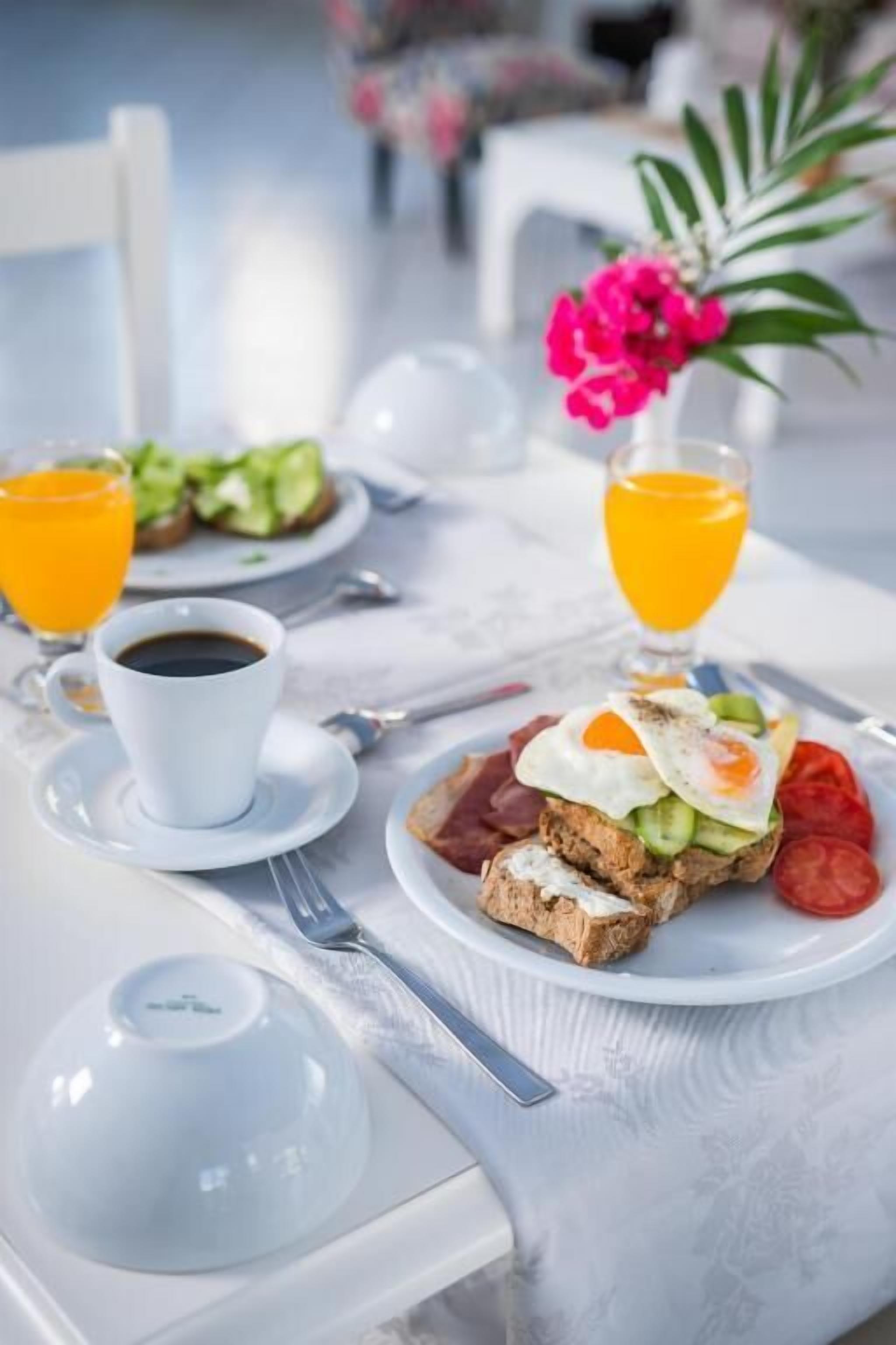 Ein Frühstückstisch mit Toast, Eiern, Tomaten, einer Kaffeetasse und einem Glas Orangensaft.