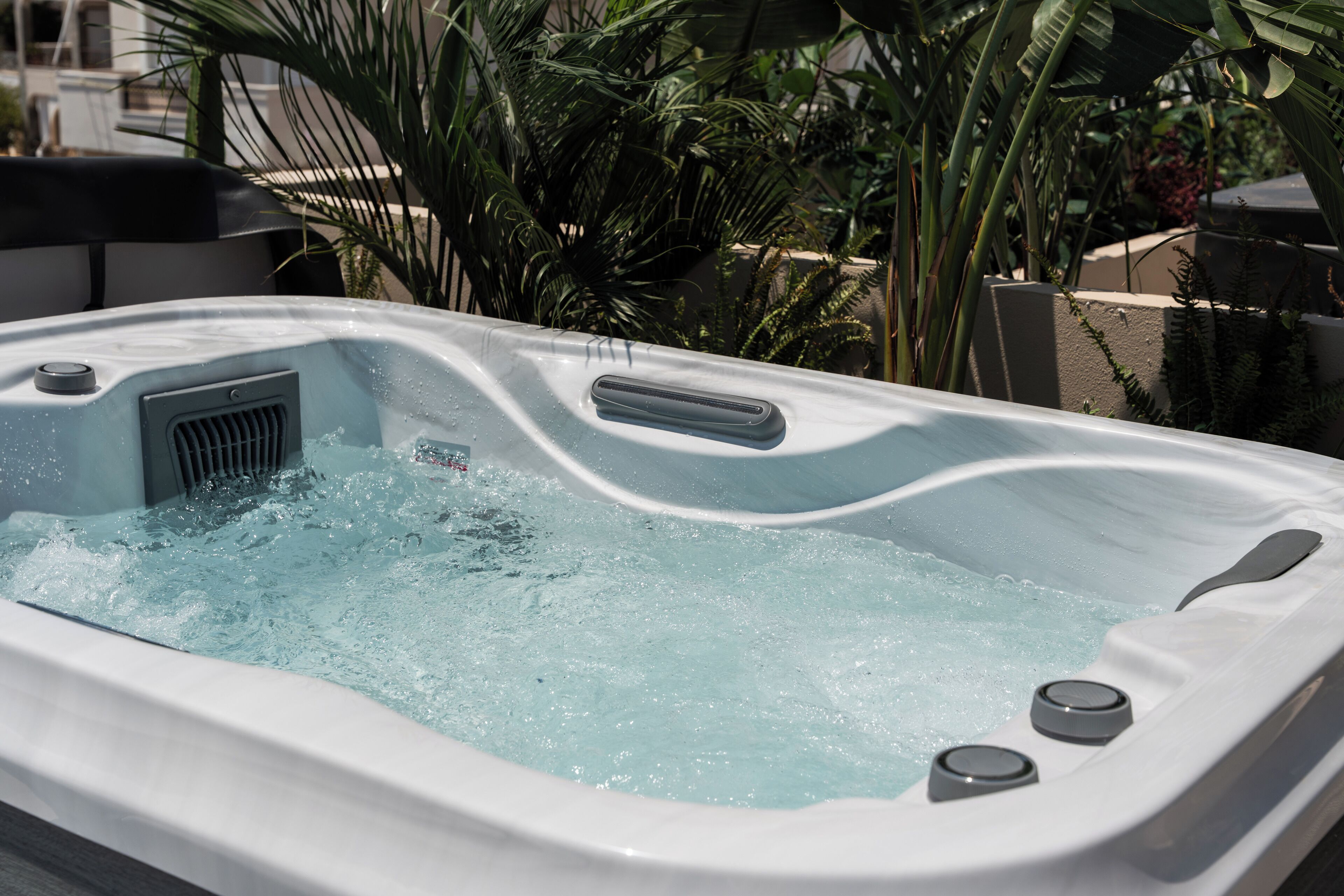 Un jacuzzi con panel de control y ventilación, rodeado de follaje.