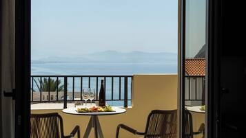 A balcony with a table set for two, a bottle of wine, and a plate of fruit.