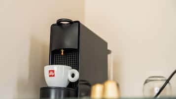 Una cafetera con una taza y una vela sobre una mesa.