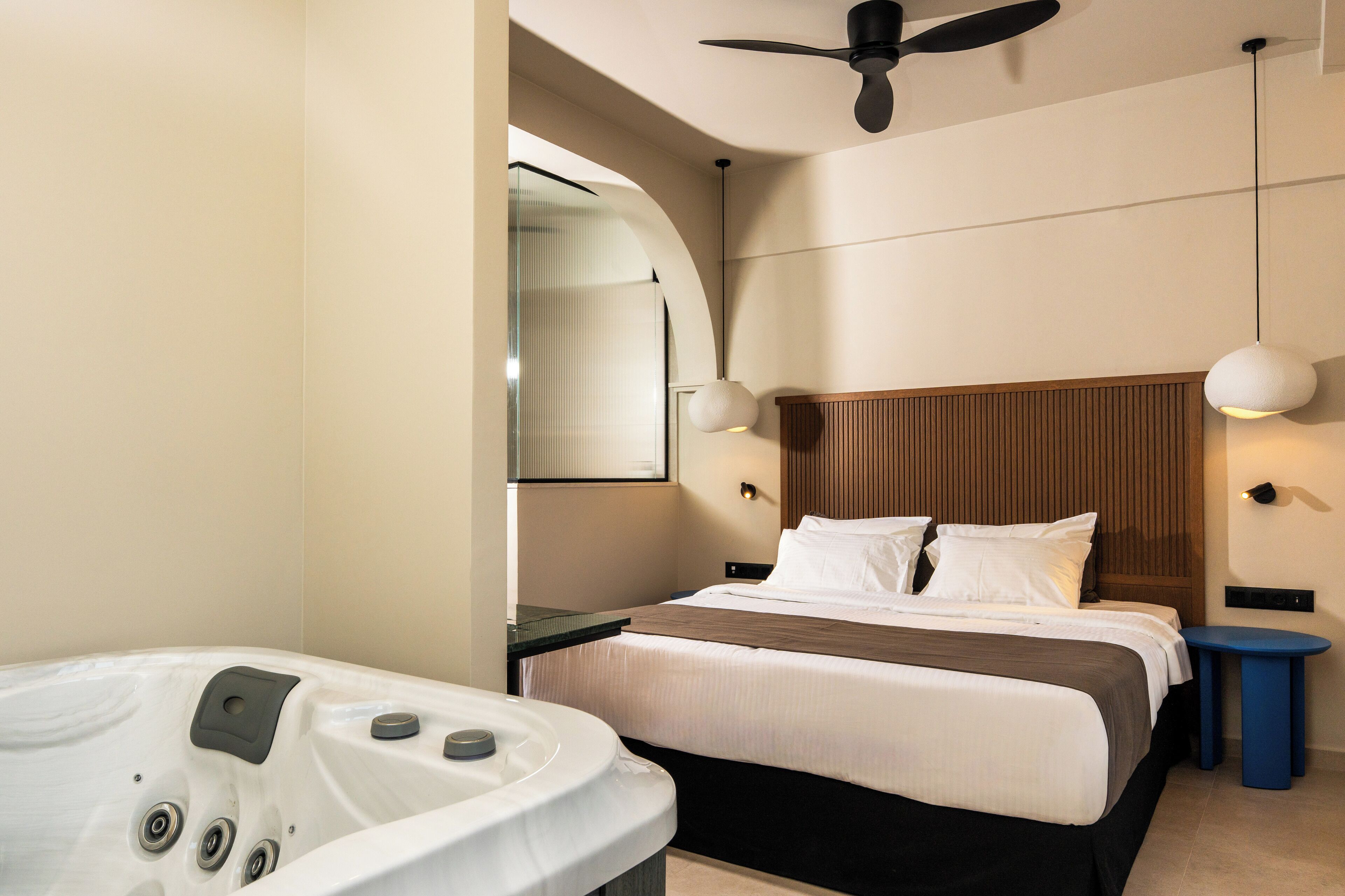 Ein modernes Hotelzimmer mit einem großen Bett, einer integrierten Badewanne und einem Deckenventilator.