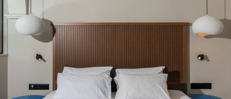 Una cama bien hecha con sábanas blancas, dos mesitas de noche y un cabecero de madera.